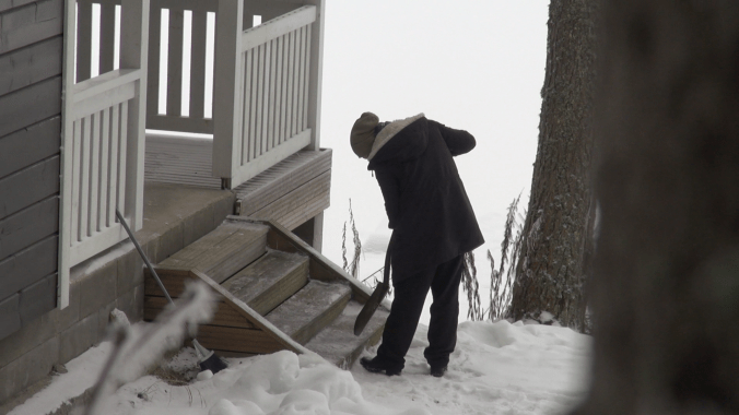 Kuvassa yhteisön asukas poistaa jäätä rappusista.