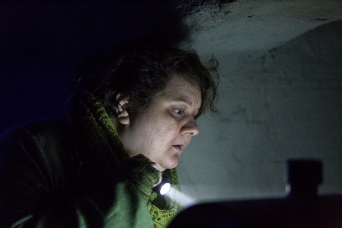 Hahmo osoittaa jotain taskulampulla ja tuijottaa intensiivisesti.