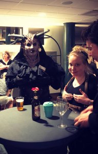 Kuvassa demoni ja MMasi Hannula pöydän äärellä pitelevät rinnuksiaan.