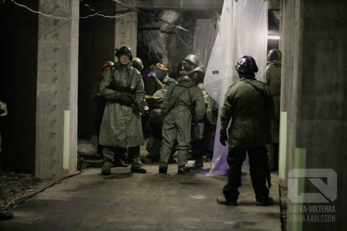 Sadesuojapuvuissa aseistettuja ihmisiä