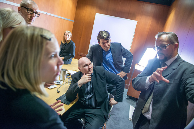 perinteisenoloisessa kuvapankkikuvassa yritysmaailman ihmiset seuraavat tarkasti esitelmän pitoa