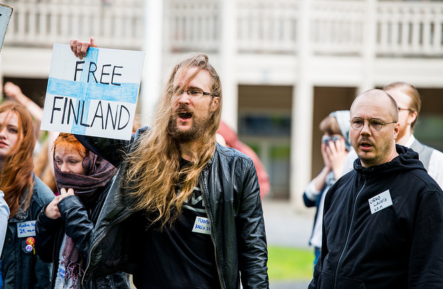 mielenosoittaja pitelee "free Finland" kylttiä ja huutaa, taustalla muita mielenosoittajia