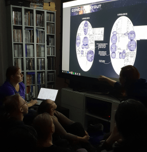 Kuvissa Mia selittää tiimille seinälle heijastettua tilasuunnitelmaa.