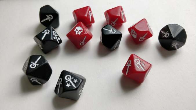 kuvassa d10 noppia, mustia ja punaisia, joiss anumeroiden sijaan on erilaisia ankh-merkkejä ja pääkalloja