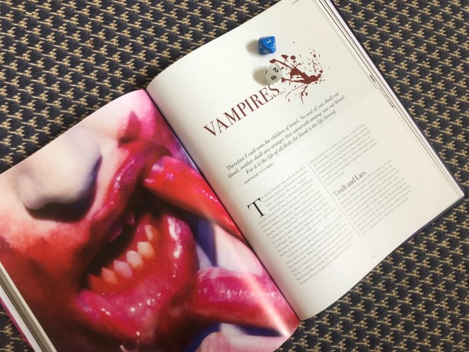 Kuvassa kirjan aukeama, jossa vasemmalla puolella on verinen vampyyrin suu, oikealla kaksi noppaa kirjan päällä ja kirjan teksti "Vampires"