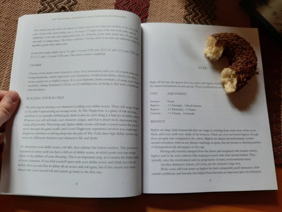 Kuvassa aukeama kirjasta, jossa karusti taitettua tekstiä ilman kuvia. Mittakaavan vuoksi donitsi. Sivut ovat n. A4-kokoa.