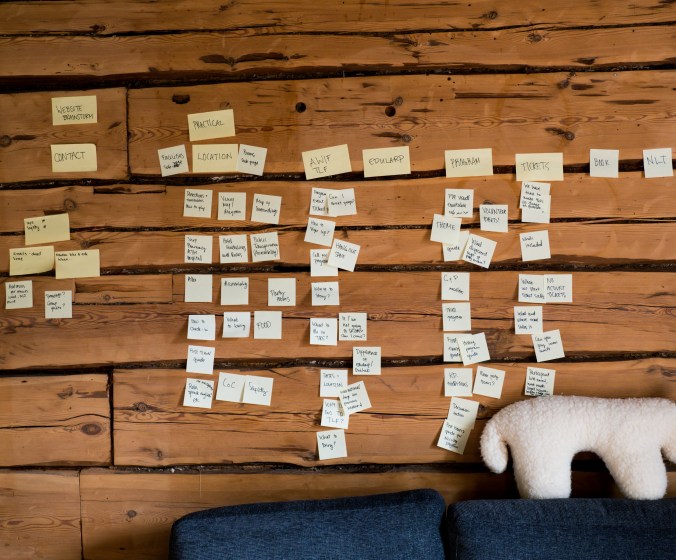 Kuvassa hirsiseinä täynnä post-it lappuja