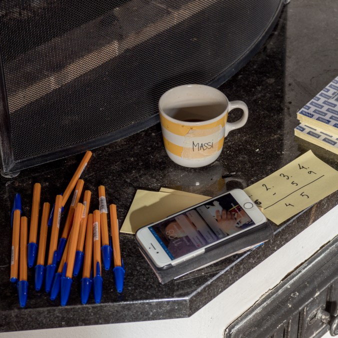 Kuvassa kuulakärkikyniä, puhelin, post-it lappuja ja kahvikuppi, jossa lukee Massi