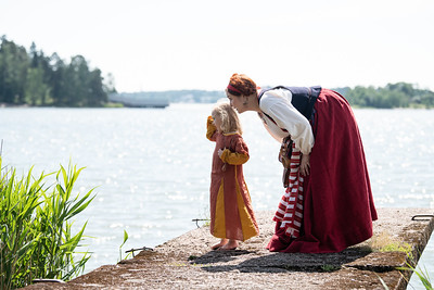 lapsi ja aikuinen naisoletettu muinaispuvuissa kivilaiturilla meren rannalla