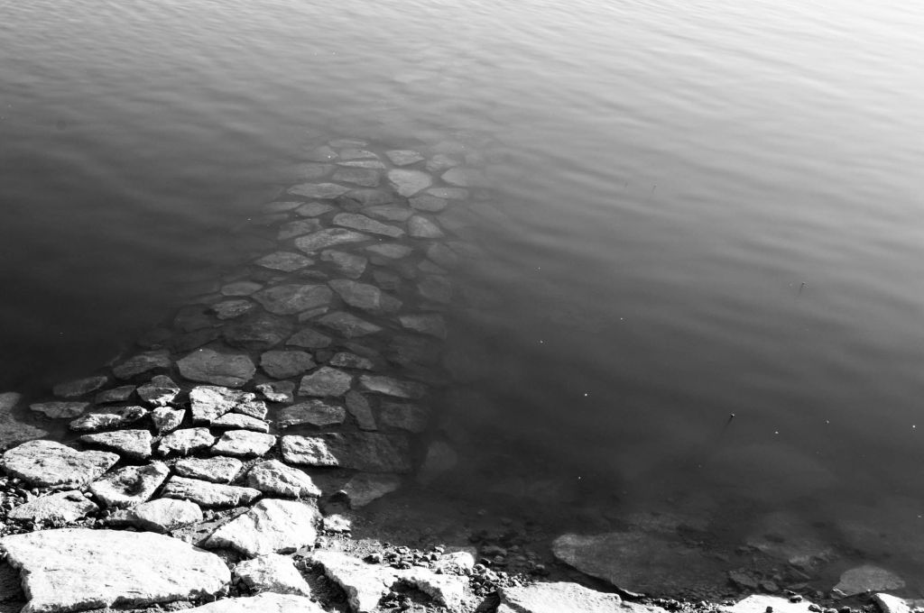 Rantakivetys muodostaa polun, joka johtaa veteen ja katoaa sinne.