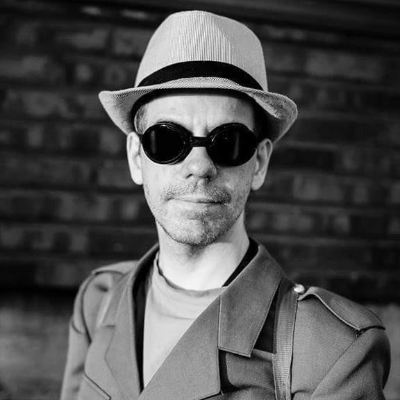 Kuvassa Mixu Lauronen tummat ajolasit ja hattu päässään.