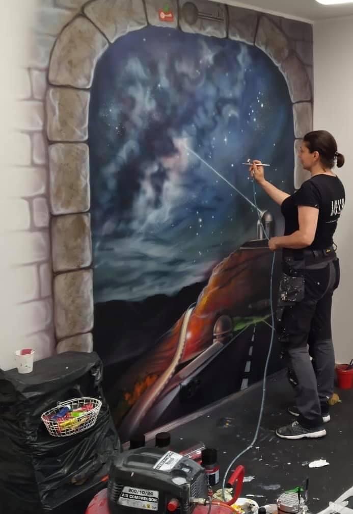 kuvassa nainen maalaa porttia, joka johtaa avaruusnäkymään.