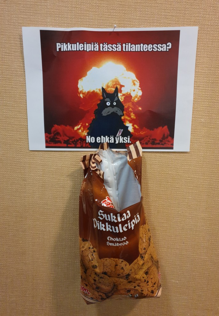 Julisteessa muumien piisamirotta on ydinräjähdys taustanaan ja sanoo "pikkuleipiä tässä tilanteessa? No ehkä yksi" alla roikkuu sulkaapikkuleipä-pussi.
