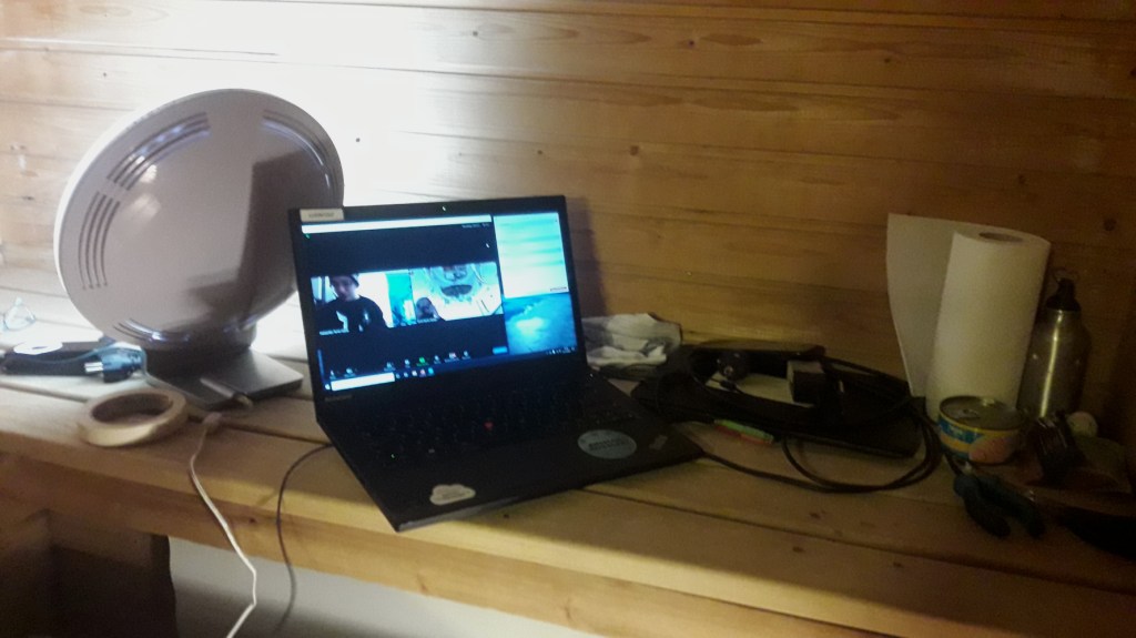 Abandon shipin pelipaikka. Kapea penkki seinän vieressä, penkillä avoin läppäri, lamppu sekä sekalaista sälää talouspaperirullasta säilykepurkkiin asti.