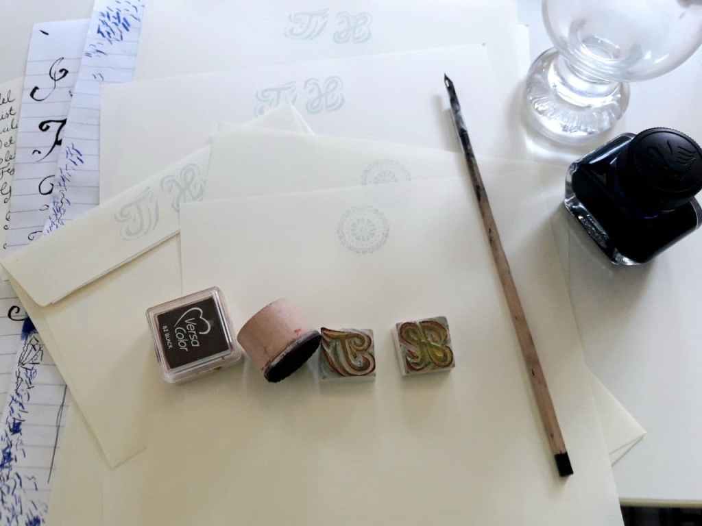 Kuvassa on vanhanaikainen mustereä, pullo mustetta ja joukko leimasimia.