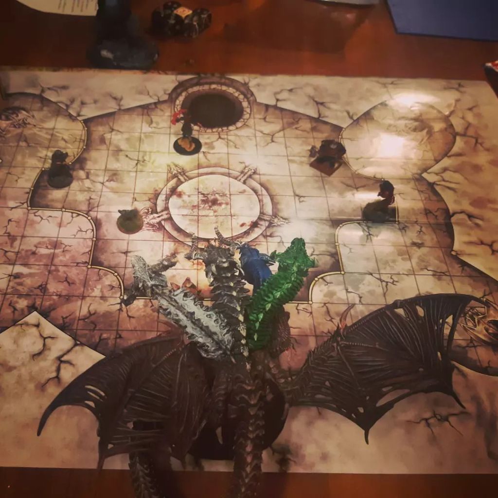 Kuvassa ruutukartta, jonka päällä on viisi pelihahmoa ja nelipäinen lohikäärme.